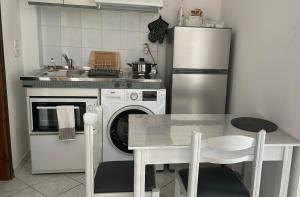伊古迈尼察ALEKA KOTSI ROOMS的厨房配有桌子和白色冰箱。