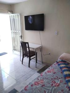 Melo BarretoLoft Itaipuaçu Maricá的一间设有一张桌子和一把椅子的房间,墙上设有一台电视机