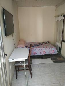 Melo BarretoLoft Itaipuaçu Maricá的小房间设有床、桌子和电视