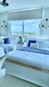 普拉亚布兰卡Exclusivo, Moderno y Cómodo Apto temático con hermosa Vista al Mar的白色卧室设有两张床和大窗户