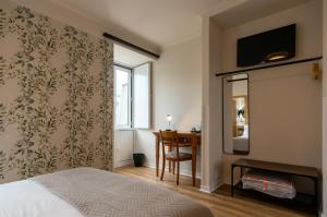 科英布拉维多利亚酒店 的一间卧室配有一张床、一张书桌和一个窗户。