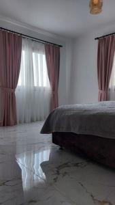 凯里尼亚Girne, Lapta'da Deniz ve Dağ Manzaralı的一间卧室配有床和两个带窗帘的窗户