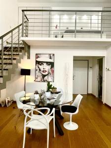 米兰Loft Milano Manifatture的一间设有玻璃桌和白色椅子的用餐室