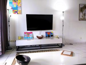 MahinaTAHITI - Amoe Condo的一间客厅,在白色的墙上配有电视