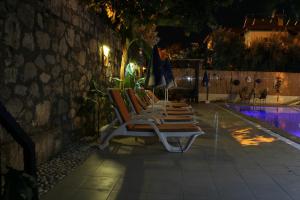 厄吕代尼兹Sarıhan Apart Otel的夜间泳池旁的一排躺椅