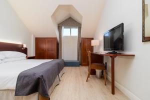 莫格罗米拉格罗斯高尔夫Spa酒店的一间卧室配有一张床和一张书桌及电视