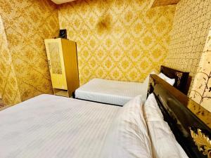 JhelumJhelum Khan Hotel的小客房内的两张床,配有黄色壁纸