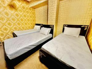 JhelumJhelum Khan Hotel的黄色墙壁客房的两张床