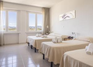 奥尔比亚狄帕兰酒店的一间设有4张床、白色床单和窗户的客房