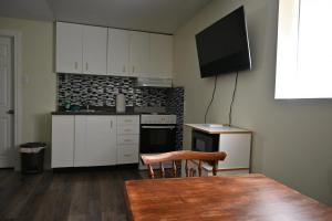 尼亚加拉瀑布Metropolitan Suite的厨房配有白色橱柜、桌子和电视。