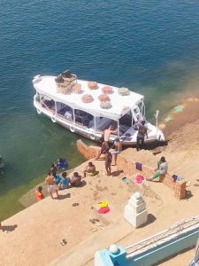 阿斯旺ABAZIDO Nubian Guest House的一群人坐在海滩上,在船边