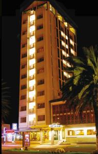 里奥班巴Hotel Zeus的一座高大的建筑,前面有一棵棕榈树