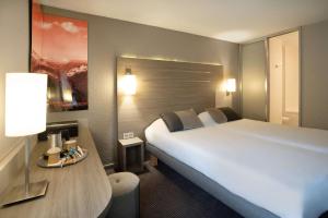 瓦龙Best Western Voiron Centre的酒店客房设有一张白色大床和一张桌子。