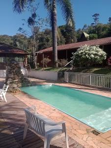 阿尤鲁奥卡Pousada nossa senhora的房屋旁的游泳池,带白色长凳
