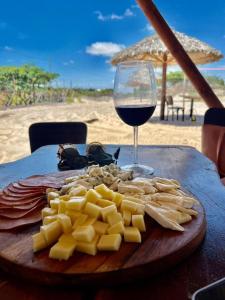 圣阿马鲁Pacas Suítes Casa & Chalés的桌上放一盘奶酪和一杯葡萄酒