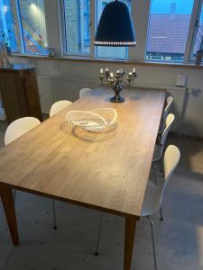 埃贝尔托夫特Ebeltoft的一张带白色椅子的木桌和一盏灯