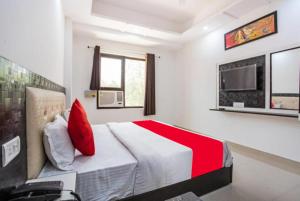 哈里瓦Hotel Raj Ganga Haridwar Near Raja Ji National park Jeep Safari - Excellent Customer Choice- Best Seller的一间卧室配有一张带红色枕头的床和一台电视。