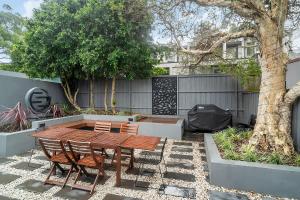 悉尼Balmain Beauty - Spacious Garden的庭院配有木桌、椅子和一棵树。
