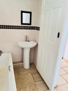 德班Frere Hill Guesthouse的一间带水槽和白色门的浴室