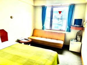 石垣岛石垣幸福假日酒店的酒店客房设有床、沙发和窗户。
