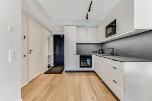 塔林15 korruse premium katusekorter的厨房配有白色橱柜和硬木地板。