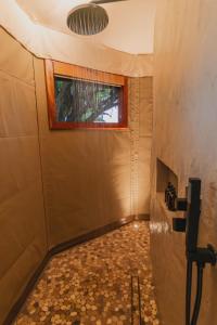 ChiawaNuyanaya River Camp的带淋浴的浴室和墙上的窗户