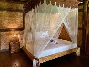 金巴兰巴拉根花蕊洋房酒店的一间卧室配有带蚊帐的天蓬床。