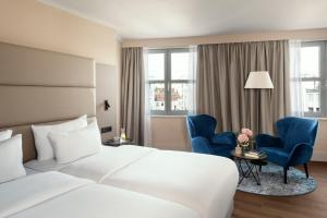 柏林NH酒店柏灵选帝侯大街店的酒店客房,配有一张床和两张蓝色椅子