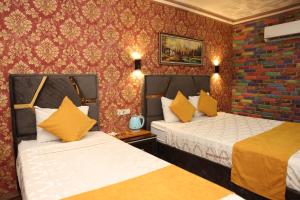 阿达纳阿达纳萨拉伊酒店的两张位于酒店客房的床铺,配有红色壁纸