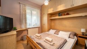 瓦茨Kútvölgy Vendégház的一间卧室配有一张床、电视和毛巾