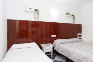 罗塔Hostal Restaurante La Giralda的一间卧室设有两张床和木墙