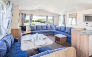 西卢港Trelawne Manor Holiday Park的大篷车客厅配有蓝色的沙发和桌子
