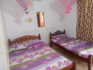 拜蒂克洛Kunam Beach Rest Inn的配有粉红色和紫色床单的客房内的两张床