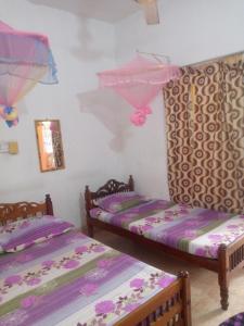 拜蒂克洛Kunam Beach Rest Inn的紫色床单的客房内的两张床