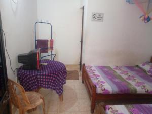 拜蒂克洛Kunam Beach Rest Inn的小房间设有两张床、一张桌子和电视