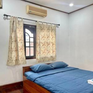 Ban NongdouangSaysouly Guest House的一间卧室设有蓝色的床和窗户。