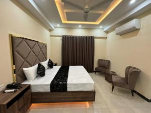 拉合尔Gold Pine Hotel Lahore的一间卧室配有一张床、一张桌子和一把椅子