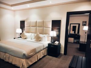 吉达فندق ميلانا Milana Hotel的一间卧室配有一张大床、两盏灯和一面镜子