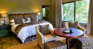 格拉罕镇African Safari Lodge的卧室配有一张床和一张桌子及椅子