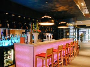 海牙海牙中心美居酒店的一间酒吧,配有橙色椅子和粉红色的柜台