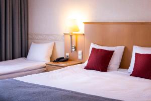 弗罗茨瓦夫Scandic Wrocław的酒店客房 - 带两张带红色枕头的床