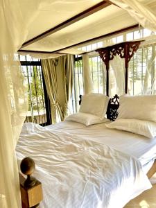 阿鲁沙Wenzi Luxury Home的配有窗户的客房内的一张带白色床单和枕头的床