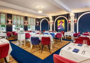 赖因斯贝格Schlosshotel Rheinsberg的一间设有白色桌子和红色椅子的餐厅