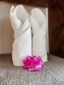 布韦朱Zanzibar Gem Beach Bungalows的地板上两条白色毛巾和一朵粉红色花