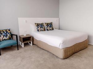 布里斯班Mercure Brisbane Spring Hill的一间卧室配有一张大床和一把椅子