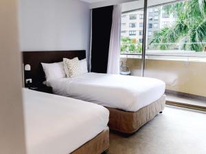 布里斯班Mercure Brisbane Spring Hill的配有窗户的酒店客房内的两张床
