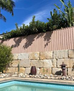 黄金海岸Relaxing Burleigh Heads Home with Swimming Pool的游泳池旁的石墙