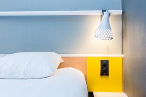 锡斯特龙西斯特龙宜必思酒店的一张带白色枕头的床和墙上的灯