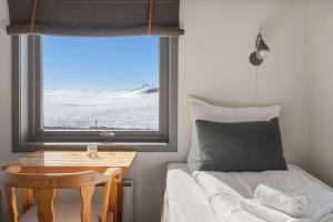 MaursetHalne Fjellstugu的一间卧室配有一张床、一张桌子和一个窗户。