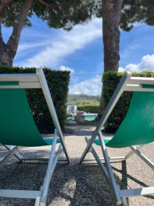 坎普码头Aviotel Residence的两把绿色和白色椅子坐在游泳池旁